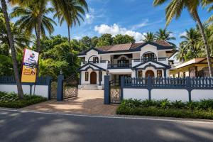 a house with a blue fence and palm trees at Triple Beach Guest House in Benaulim