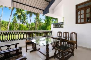 a dining room with a table and chairs and palm trees at Triple Beach Guest House in Benaulim