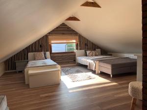 a attic bedroom with two beds and a couch at Dom Na Wsi z Balią Ogrodową-Jacuzzi in Mierzwin Duży