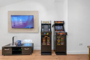 two arcade video game machines sitting next to a table at Private Double Room in Spacious House with Garden in Blackrod