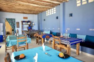 a dining room with blue walls and wooden tables at Sawa Sawa Beach House in Msambweni
