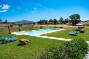 a swimming pool in a grassy yard with two picnic tables at Agriturismo Piperedda in Irgoli