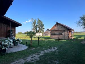 a farm with two barns and a tractor in a field at Dom Na Wsi z Balią Ogrodową-Jacuzzi in Mierzwin Duży