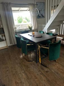 a dining room table with green chairs and a window at Charmigt hus uthyres in Holsljunga +11 photos
