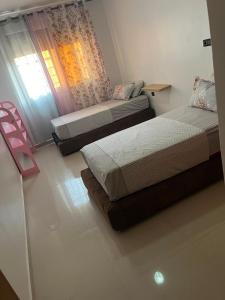 two beds in a room with a window at Appartement proche toutes commodités in Berkane +6 photos