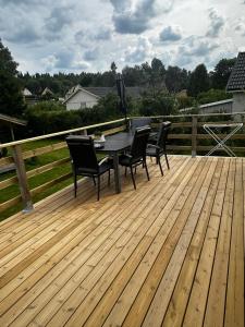 a wooden deck with a table and chairs on it at Charmigt hus uthyres in Holsljunga