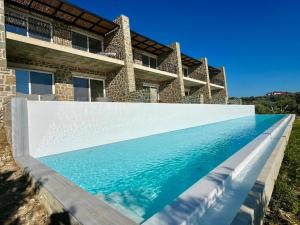 a swimming pool in front of a house at Rea's Luxury Suite Gialova in Gialova