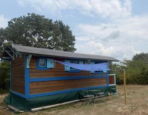 a tiny house with a gambrel roof and blue trim at La Roulotte à Raven in Le Houga