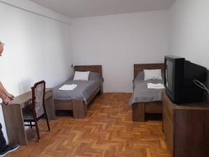 a small room with two beds and a tv at Peregrino Vendégház in Budaörs