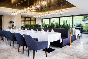 ein Esszimmer mit weißen Tischen und blauen Stühlen in der Unterkunft Hotel Porto in Plungė