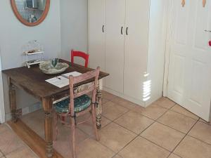 a room with a wooden table with a chair and white cabinets at Nouvelle Vie Self-catering Accommodation in Reebok