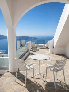 a patio with two chairs and a table on a balcony at Santorini Theasis Suites in Imerovigli