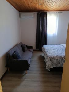 a bedroom with a bed and a couch and a window at LaKaz Pascale T2 climatisé pour 4 adultes 1 enfant in Ravine des Cabris