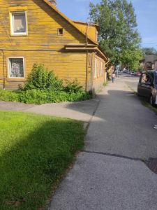 a road next to a yellow building with a car parked next to it at Korter in Tartu