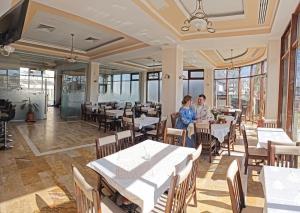 two people sitting at tables in a restaurant at Alma by iVAVev in Mamaia
