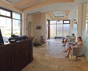 two people sitting in chairs in a lobby with a tv at Alma by iVAVev in Mamaia