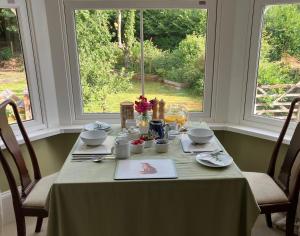 a dining room table with a green table cloth and two windows at Watercombe House in Wheddon Cross +6 photos