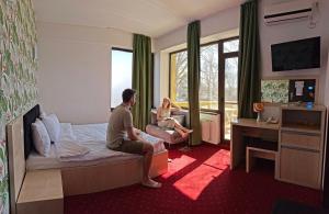 a man and woman sitting on a bed in a hotel room at Alma by iVAVev in Mamaia