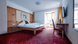 a bedroom with a bed and a desk and a chair at Hotel Alpina in Ischgl