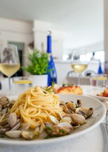a plate of pasta with clams and a glass of wine at Hotel Leonardo da Vinci in Pesaro