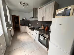 a kitchen with white cabinets and a white refrigerator at Charme et confort - Maison Roubaix 5 chambres in Roubaix