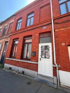 a red brick building with a white door at Charme et confort - Maison Roubaix 5 chambres in Roubaix