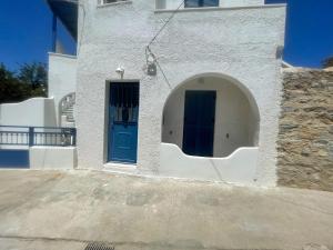 a white building with a blue door on the side at Blue Door Hideaway in Moutsoúna