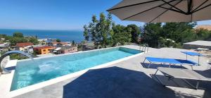 a swimming pool with two chairs and an umbrella at Hyka Stone House Shkoder in Shkodër