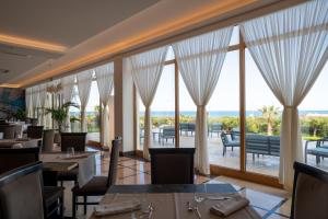 a restaurant with tables and chairs and large windows at Hotel Scoglio Degli Achei in Torre Santa Sabina