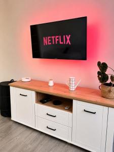 a tv on a wall with a netflix sign on it at Bricks Pérignon - Tram, lit Queen size & air fryer in Chenôve