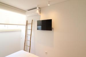 a room with a television on a wall with a ladder at Tinico's Guest Rooms in Nazaré