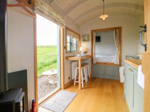 a tiny house with a kitchen and a table with a window at Meadow Shepherds Hut in Ashbourne