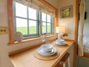 a dining room table with two plates and a lamp at Meadow Shepherds Hut in Ashbourne +14 photos