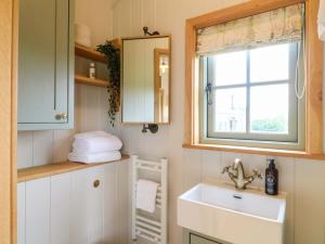 a bathroom with a sink and a window at Meadow Shepherds Hut in Ashbourne