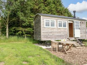 a tiny house with a picnic table in front of it at Meadow Shepherds Hut in Ashbourne