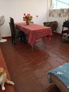 a table with a red table cloth and a cat on the floor at Hospedaje Marita in Lima