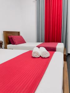 two towels on two beds in a room with red curtains at Double T in Dickwella