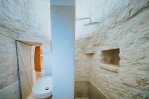 ein Badezimmer mit Toilette und einer Steinwand in der Unterkunft Trullo Cervillo in Cisternino + 47 Fotos