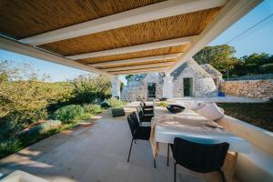 eine Terrasse mit Tisch und Stühlen unter einer Pergola in der Unterkunft Trullo Cervillo in Cisternino