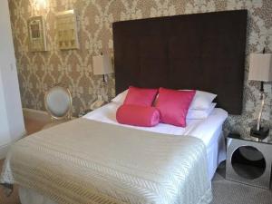 a bedroom with a bed with two pink pillows at Episode Hotel in Leamington Spa