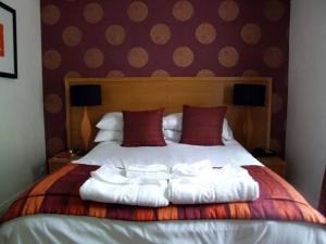 a bedroom with a large bed with red pillows at Episode Hotel in Leamington Spa
