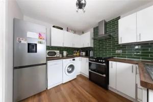 a kitchen with white appliances and green tiles at Entire 3 bedroom house in Luton