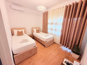 a small room with two beds and a window at Citrus Nest in Berat