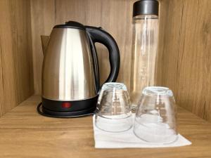 a tea kettle and two glasses on a table at Citrus Nest in Berat