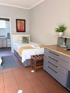 a small bedroom with a bed and a kitchen at Dew Drop Inn in Nelspruit