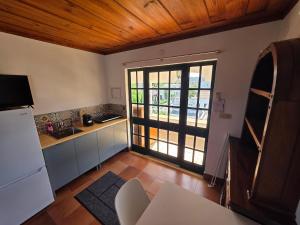 a kitchen with a refrigerator and a door to a patio at Cantinho nas Varzeas in Loulé