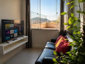 a living room with a couch and a large window at New Sugar Loft Apartments in Rio de Janeiro