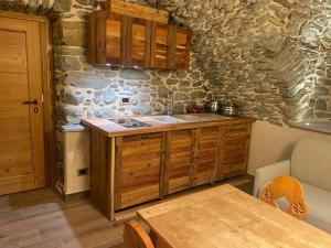 a kitchen with wooden cabinets and a stone wall at Affittacamere L'Abri in Etroubles