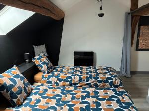 a bedroom with a bed with a comforter and pillows at L'Alcôve, maison d'artistes in Sacquenay