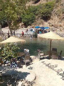 a beach with chairs and umbrellas and people in the water at مخيم اقشور in Chefchaouen